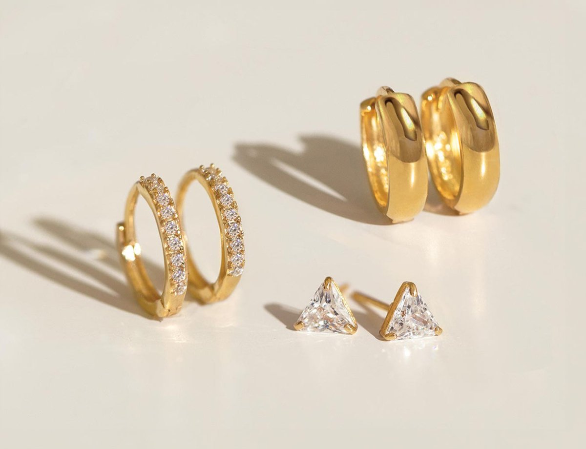 Elegant 14K gold earrings including thin pave huggie hoops, classic mini hoops, and tiny sapphire studs from AMYO Jewelry
