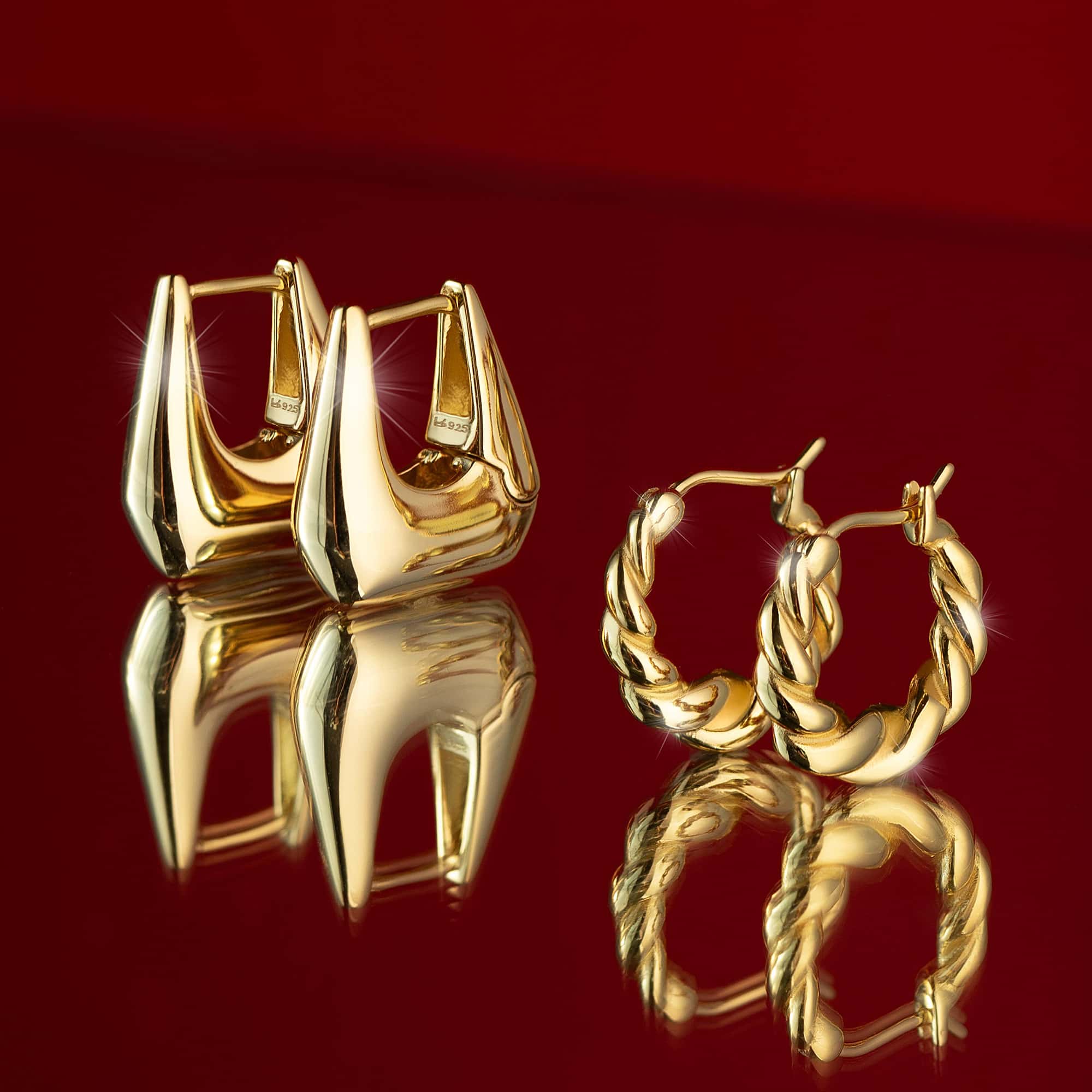 Two pairs of gold hoop earrings on a red background from AMYO.