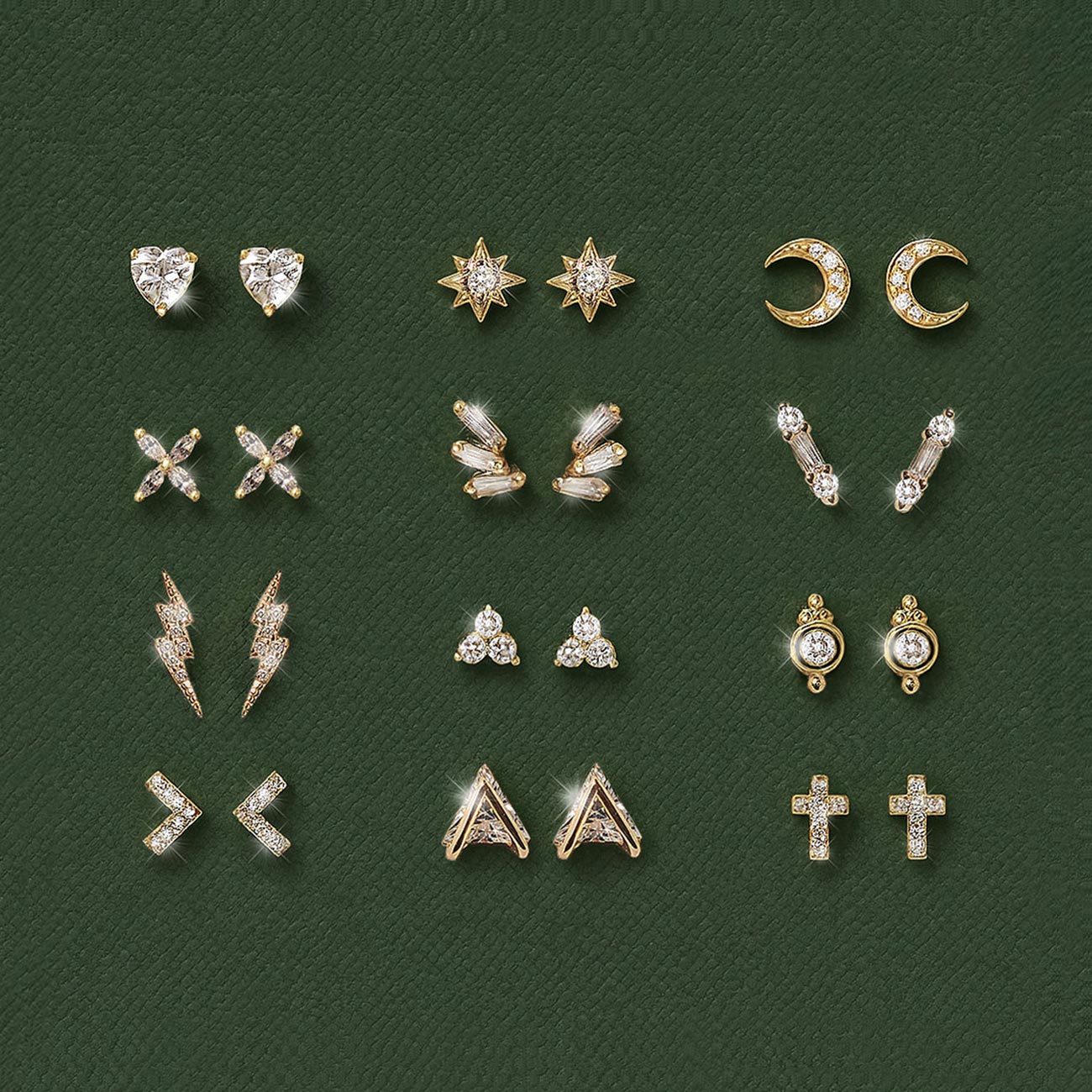 Collection of various tiny gold stud earrings from AMYO on a green textured background.