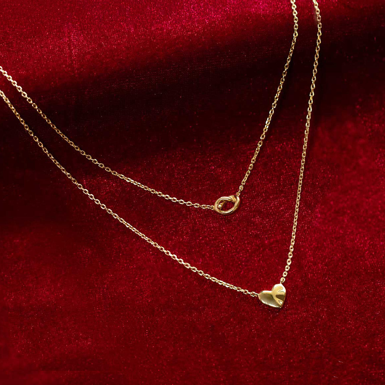 Shop AMYO gold pendant necklaces styled on red velvet, a timeless dainty piece perfect for layering, everyday wear, or as a meaningful jewelry gift.