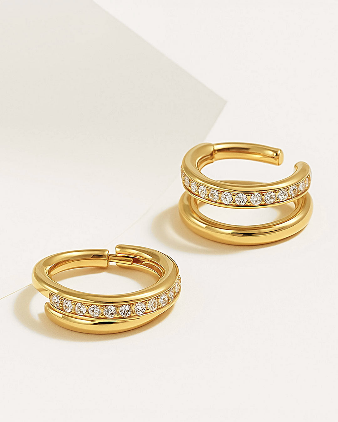 Gold cartilage hoop earrings with crystal accents on a light background