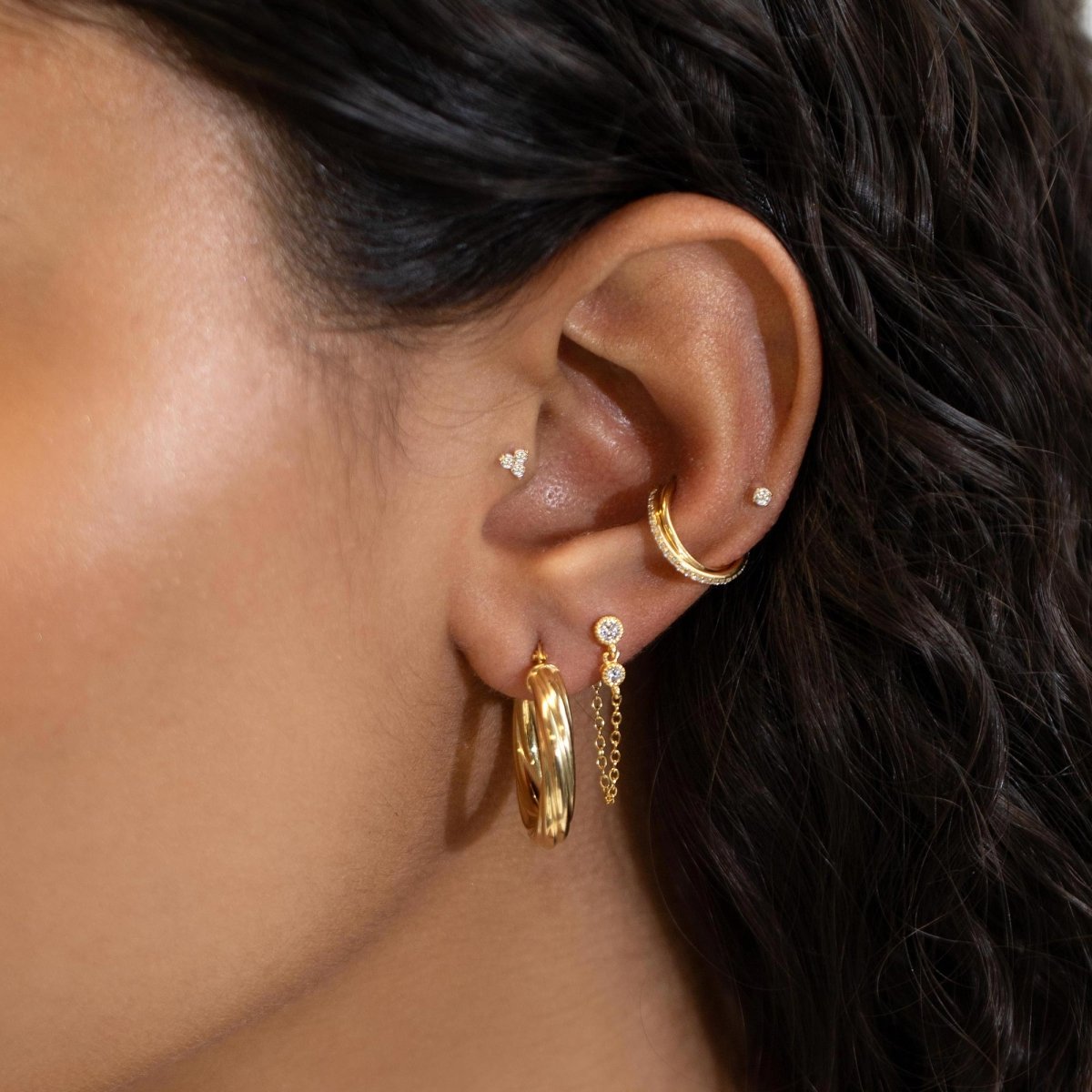 Gold vermeil thick twisted hoop shown on a model's lobe with stud and chain earrings stacked above