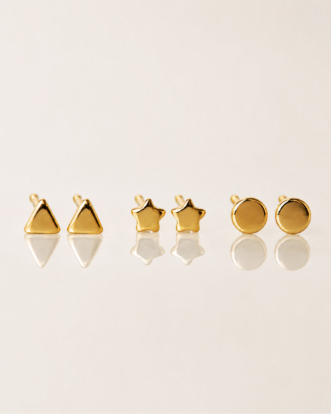 Set of tiny gold stud earrings in various shapes like stars, cirles and triangles from AMYO.