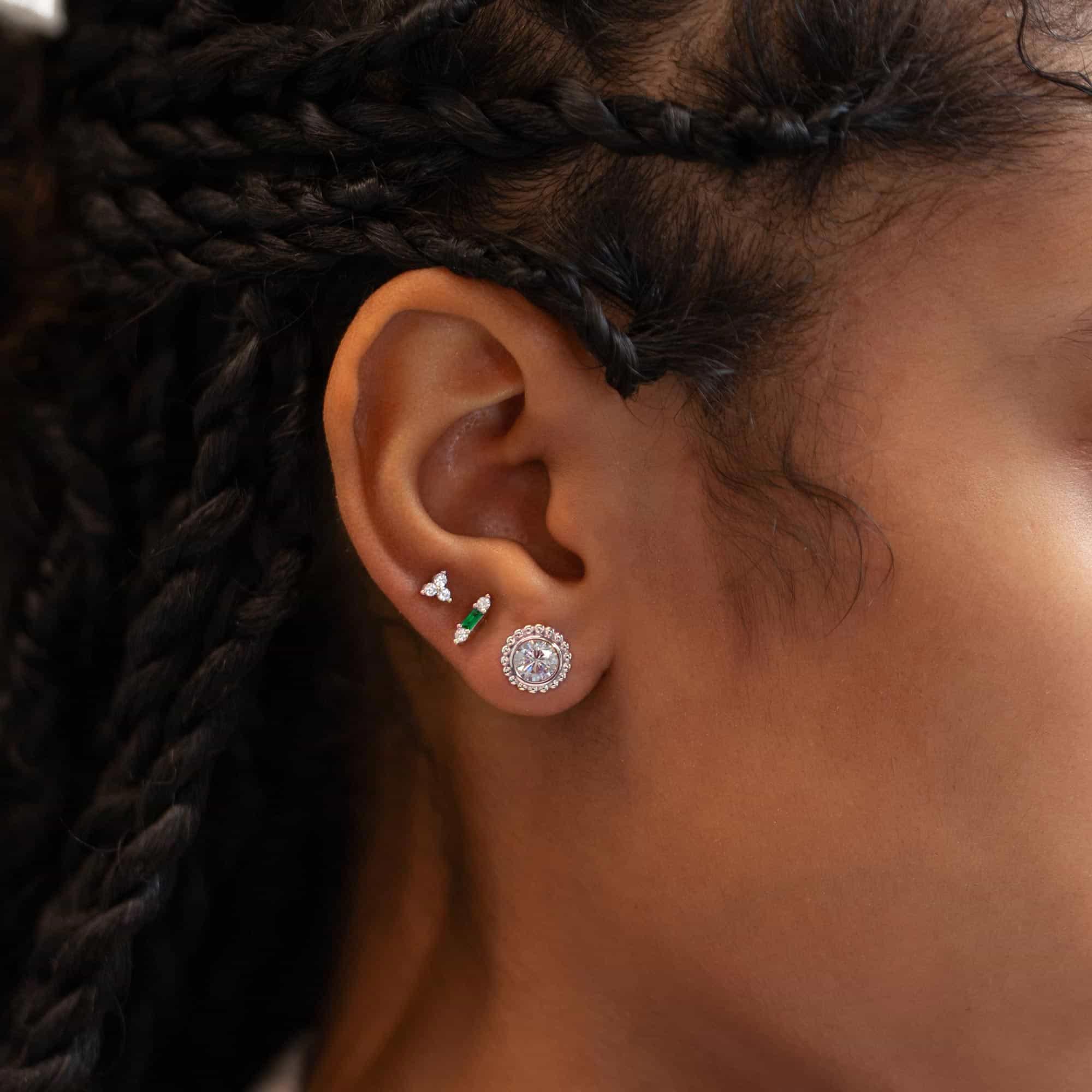 Close up of woman's ear featuring Sterling Silver Gemstone Bar + Clover Studs Set Emerald and big circle earring