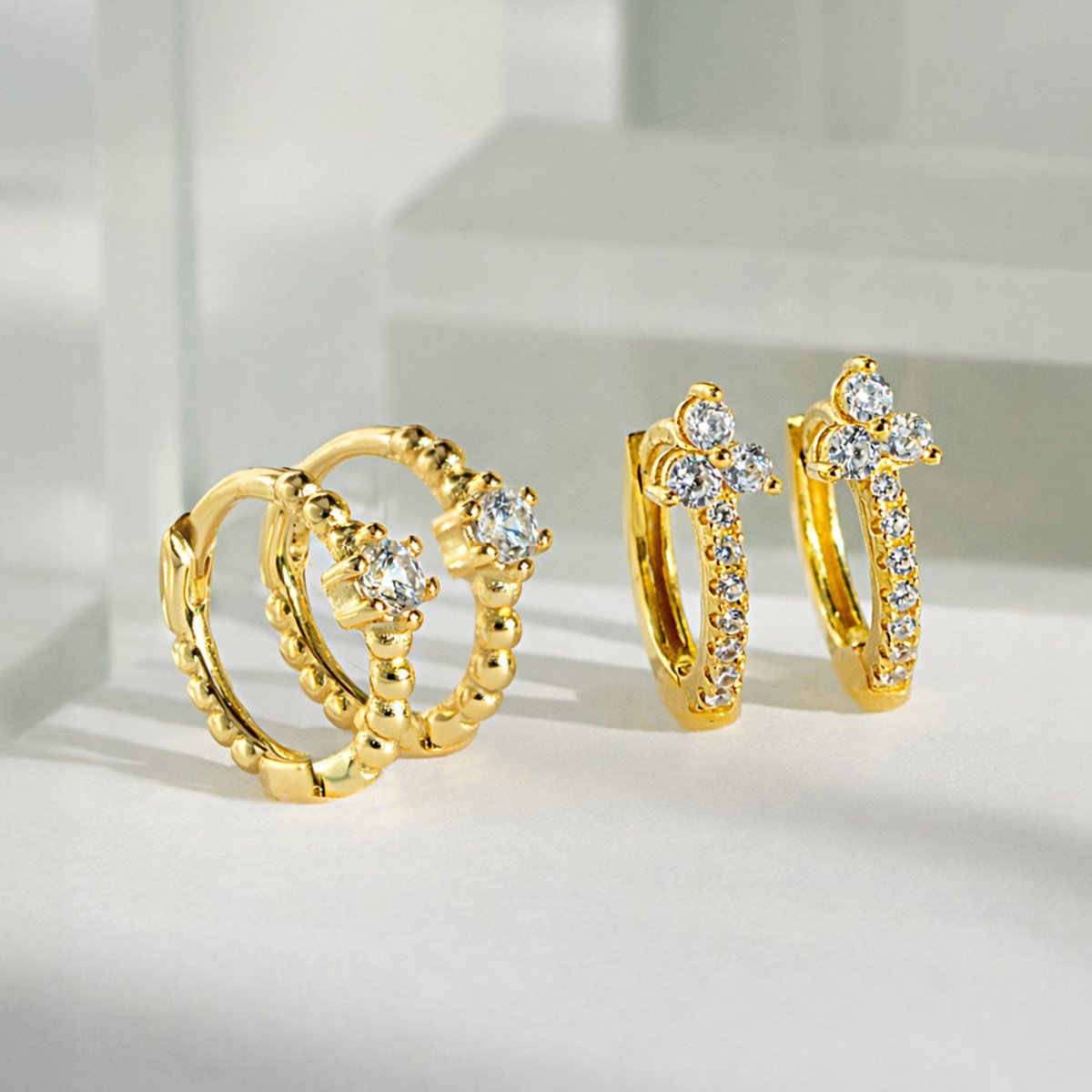 AMYO gold vermeil huggie earrings with crystal accents, featuring textured and pavé designs, styled as timeless everyday earrings perfect for gifting.
