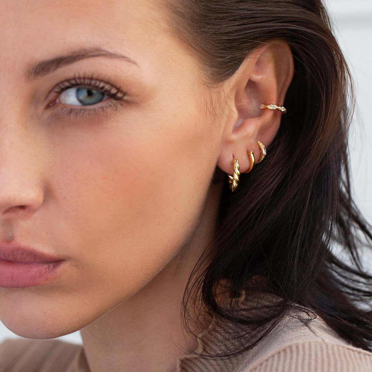 Gold vermeil twisted rope huggie hoop shown on a model's lobe in a curated ear stack
