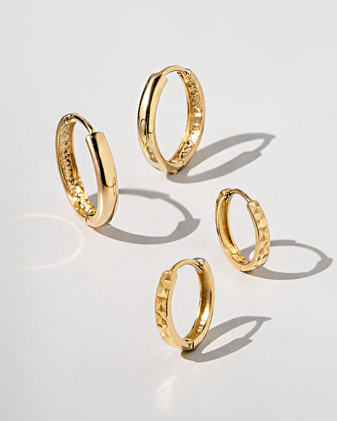 14K gold huggie earrings with polished and textured finishes. Shop AMYO gold earrings.