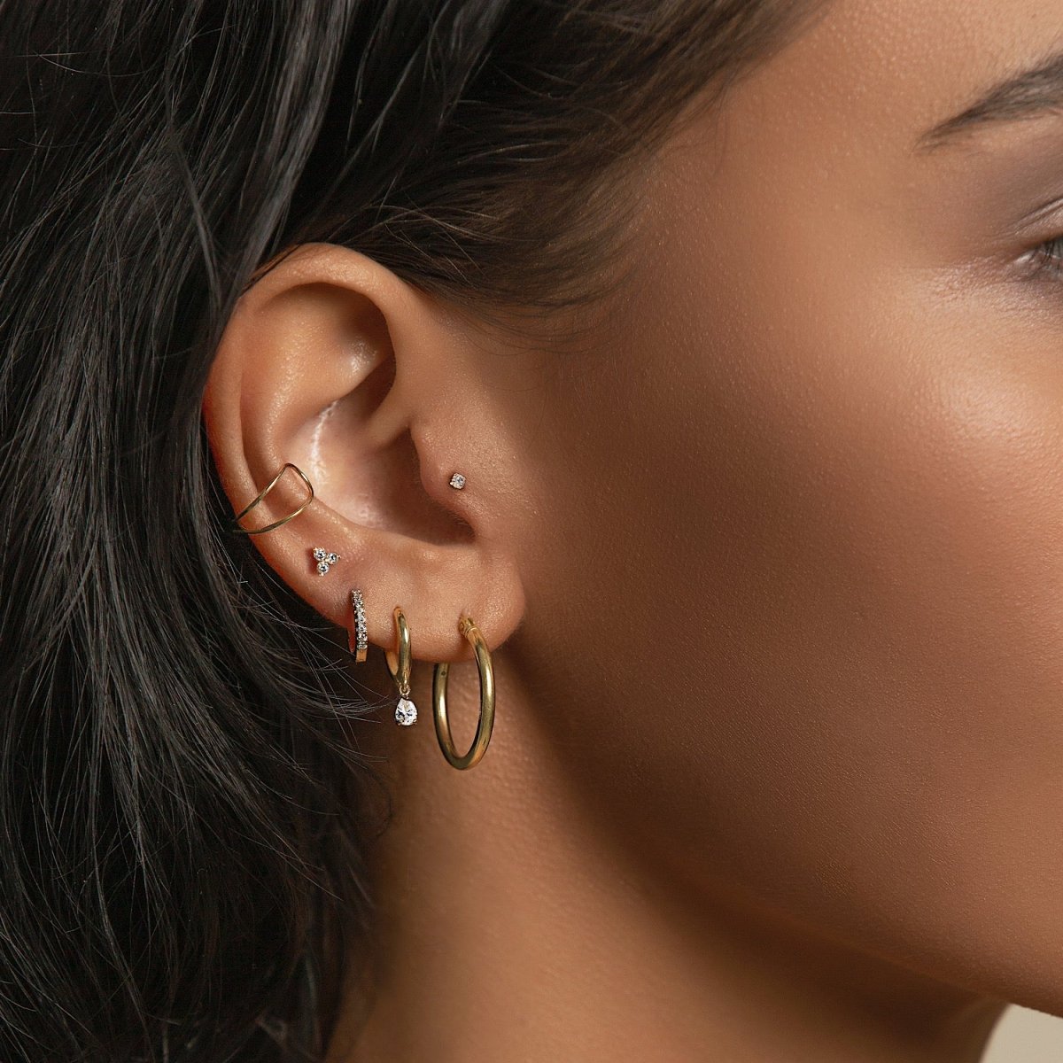14K gold pavé huggie hoop with clear stones styled in a gold ear stack, shown on a model