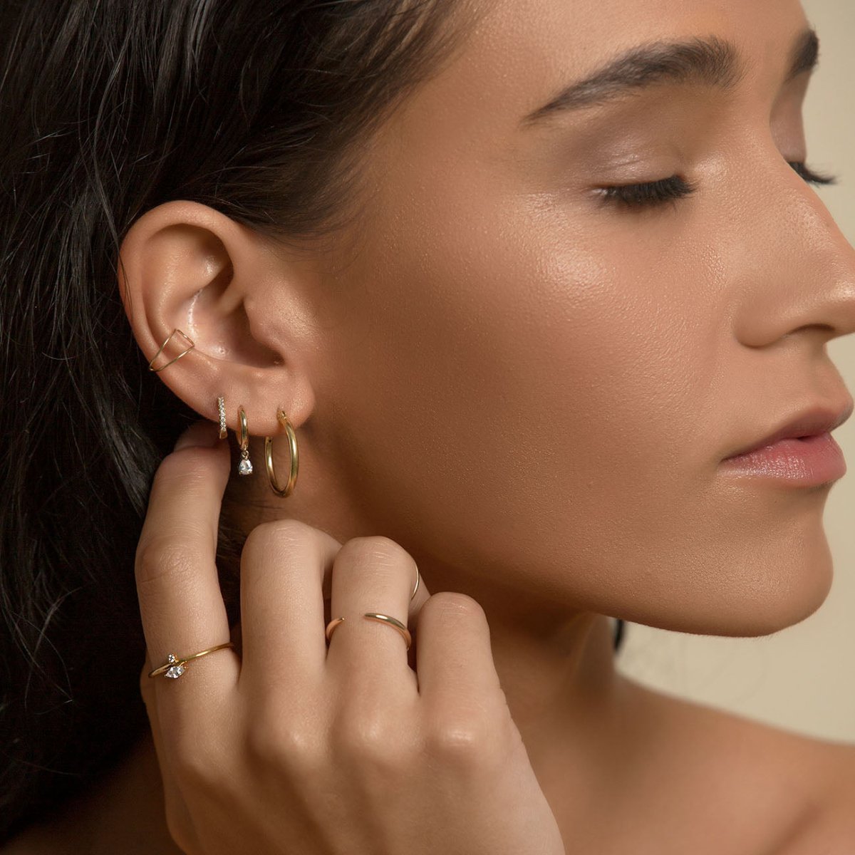 14K gold pear-drop moissanite huggie hoop shown in a stacked ear on a model
