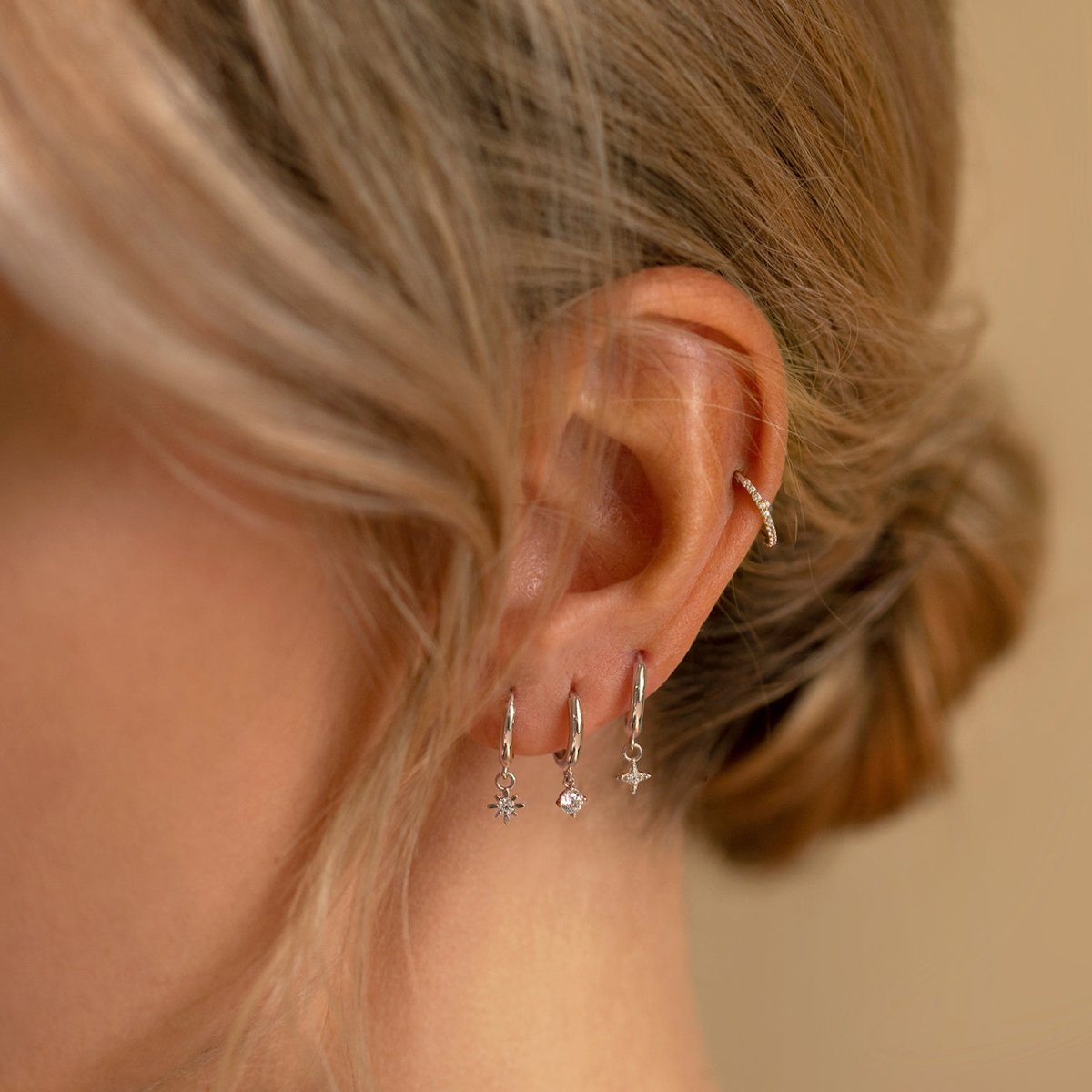 14K white gold huggie hoops with dangling zirconia charms, shown on a model's lobes