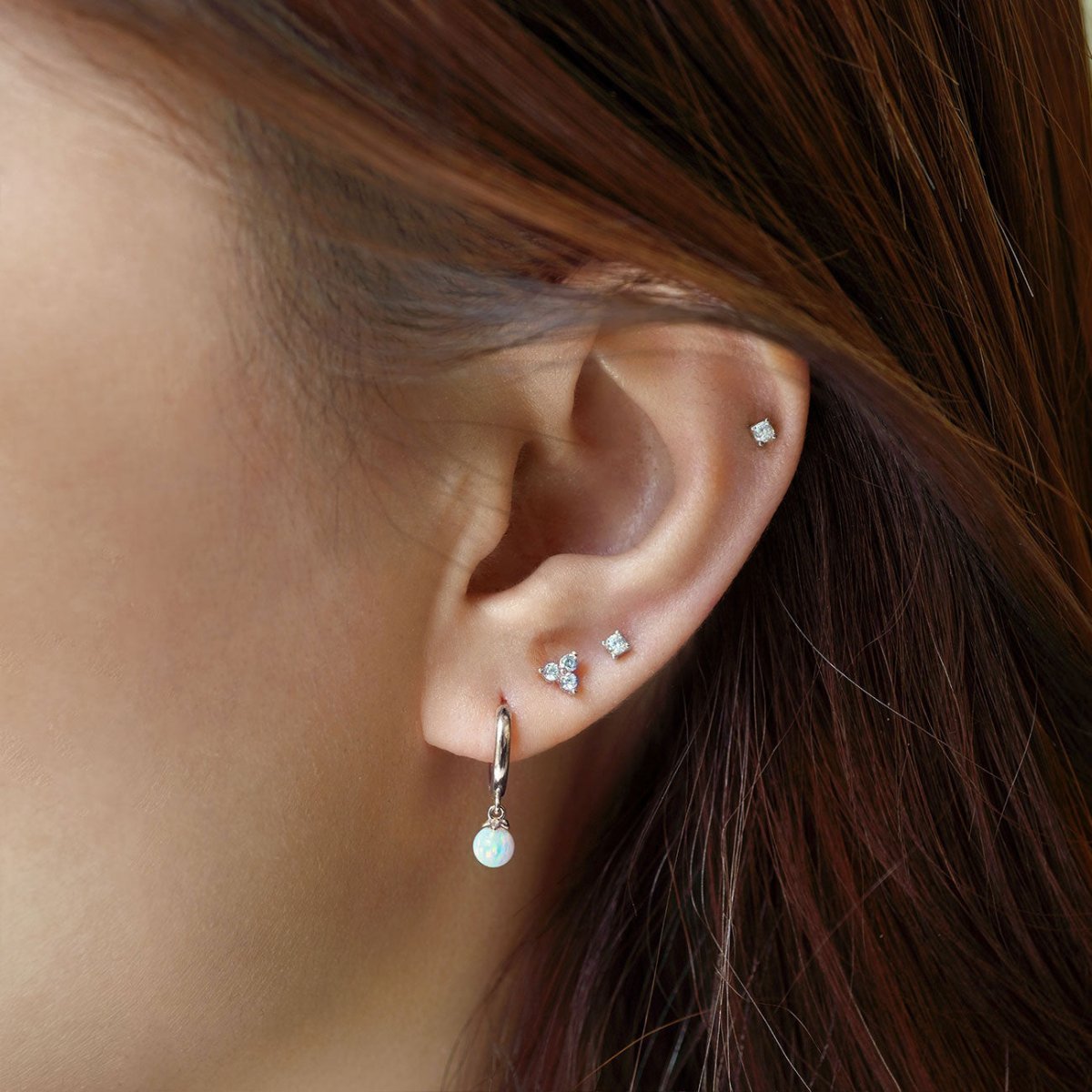 Close up of woman's ear featuring Sterling Silver Gemstone Clover Studs Aquamarine and opal hoop earring