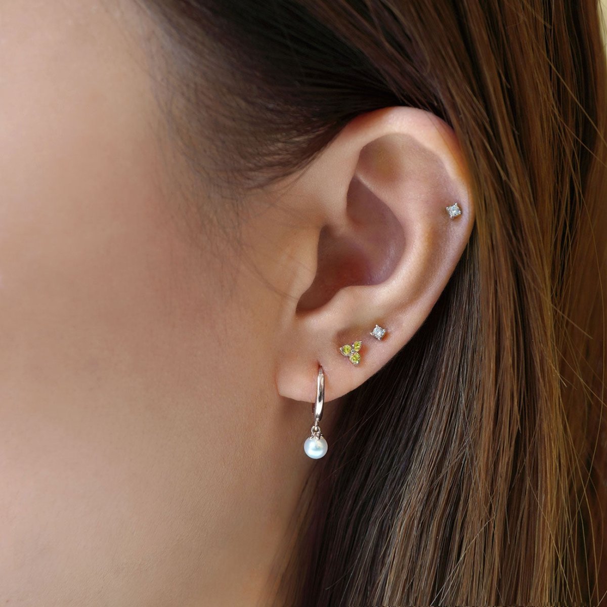Close up of woman's ear featuring Sterling Silver Birthstone Studs Set Peridot and opal hoop earring