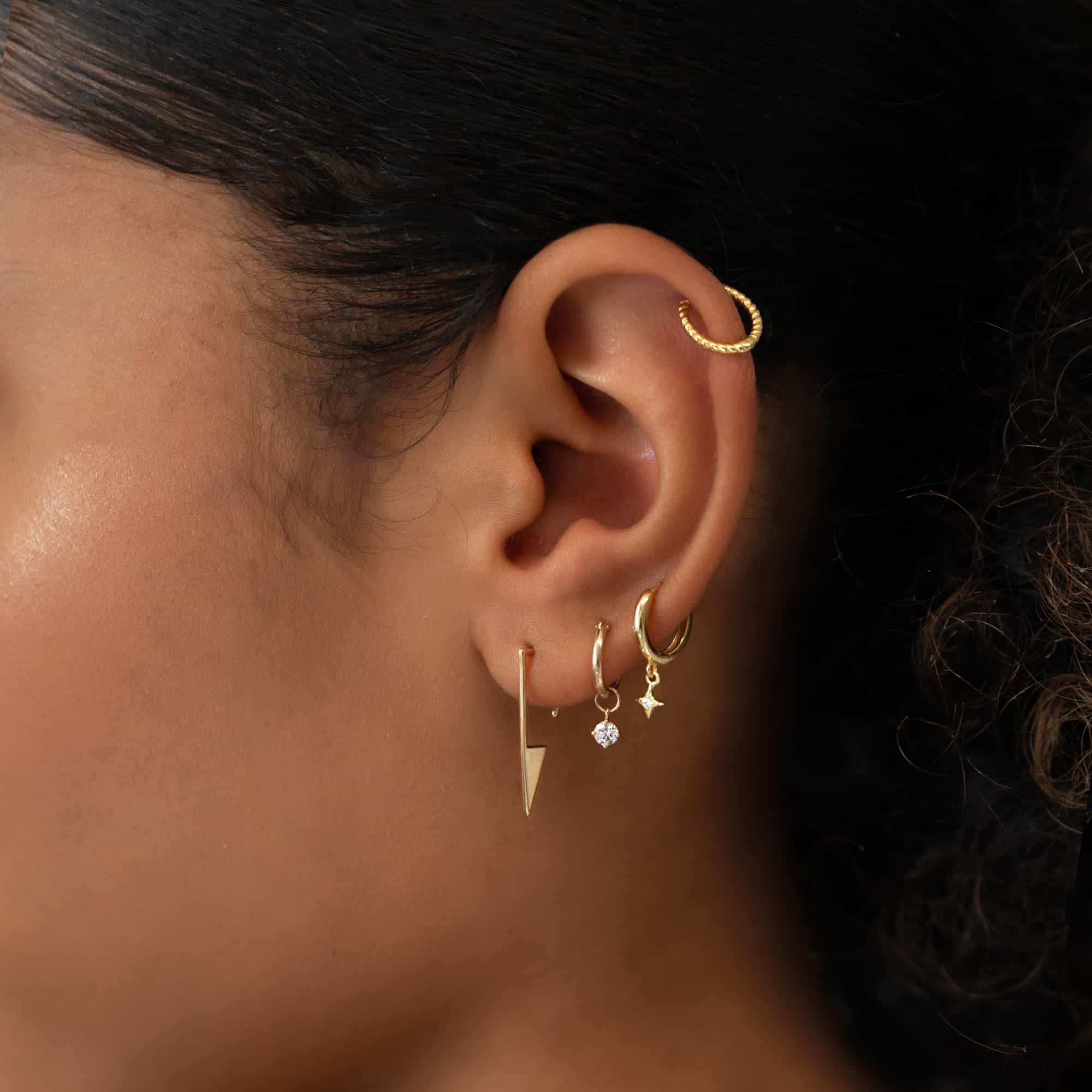 Close-up of ear featuring Single Gold Rope Textured Cartilage Huggie Hoop and other dazzling lobe earrings
