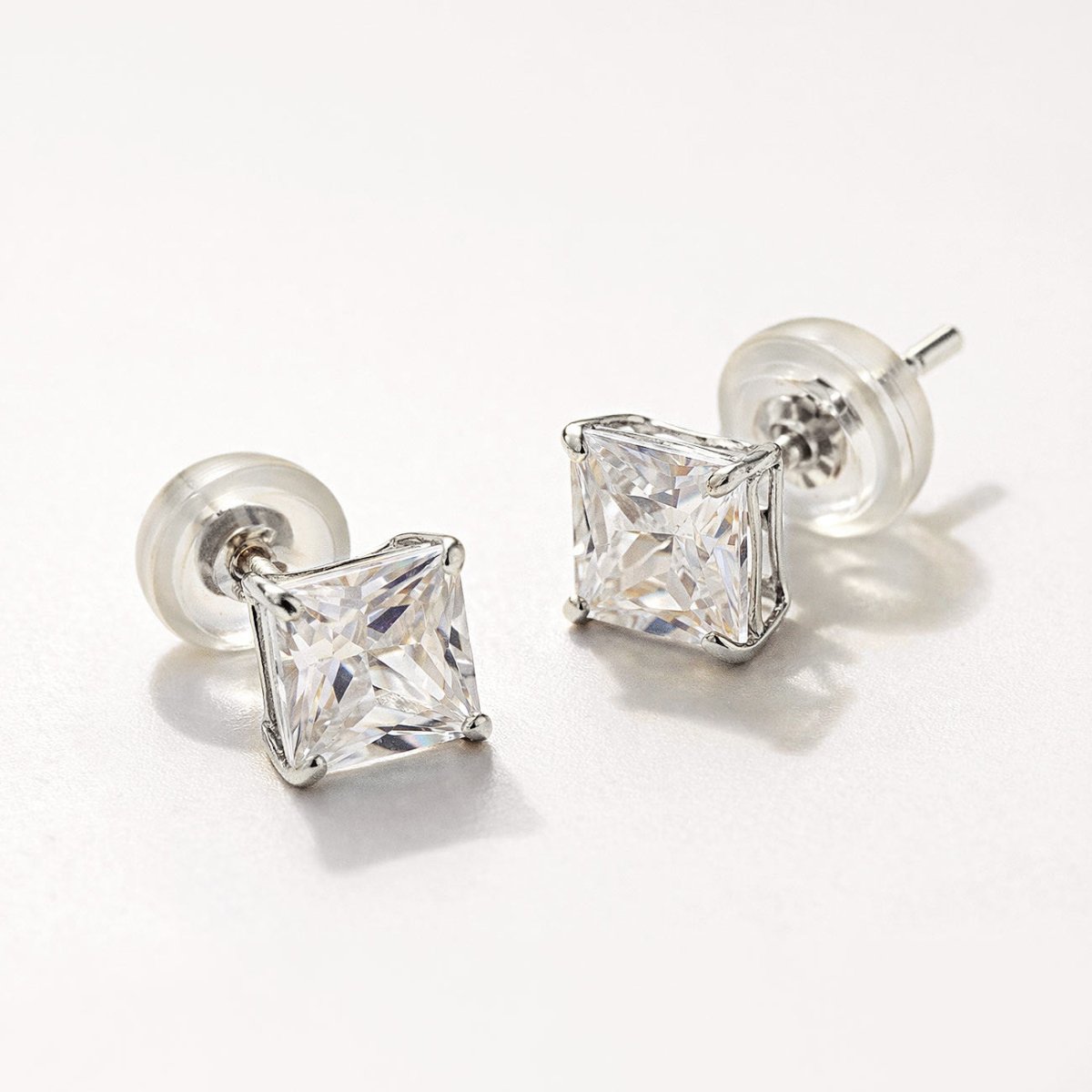 A pair of 14K White Gold Princess Cut stud earrings with white zirconia gemstone and silicone earring backs from AMYO.