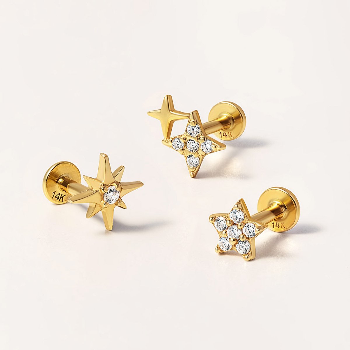 Detailed shot of 14K Gold star-shaped flat back earrings from AMYO with cz crystals on a light background
