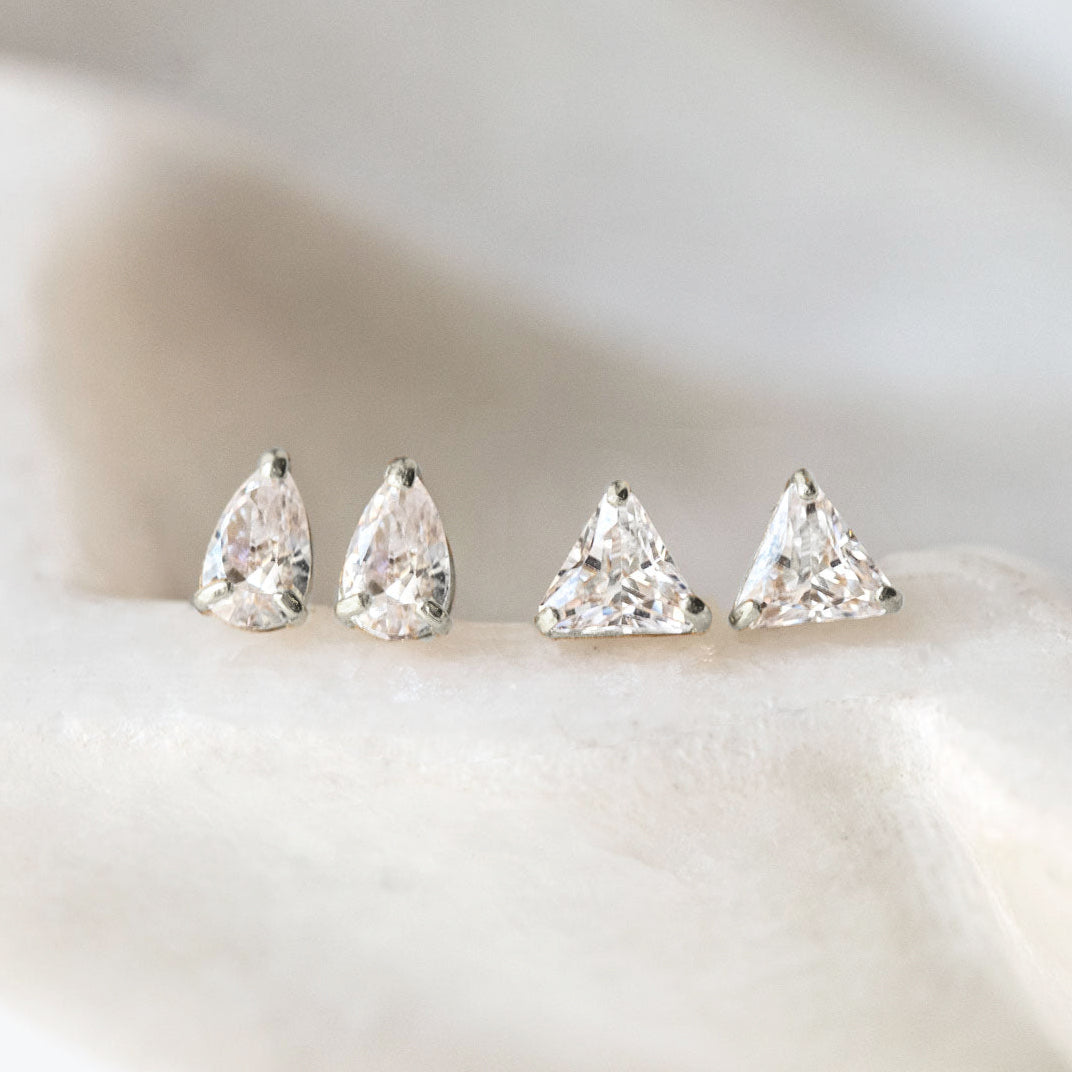 Four AMYO diamond earrings on a light background