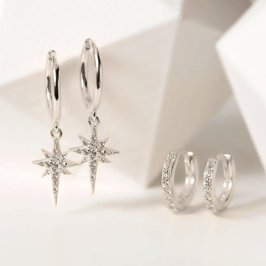 AMYO Silver hoop earrings with star-shaped pendants on a light background