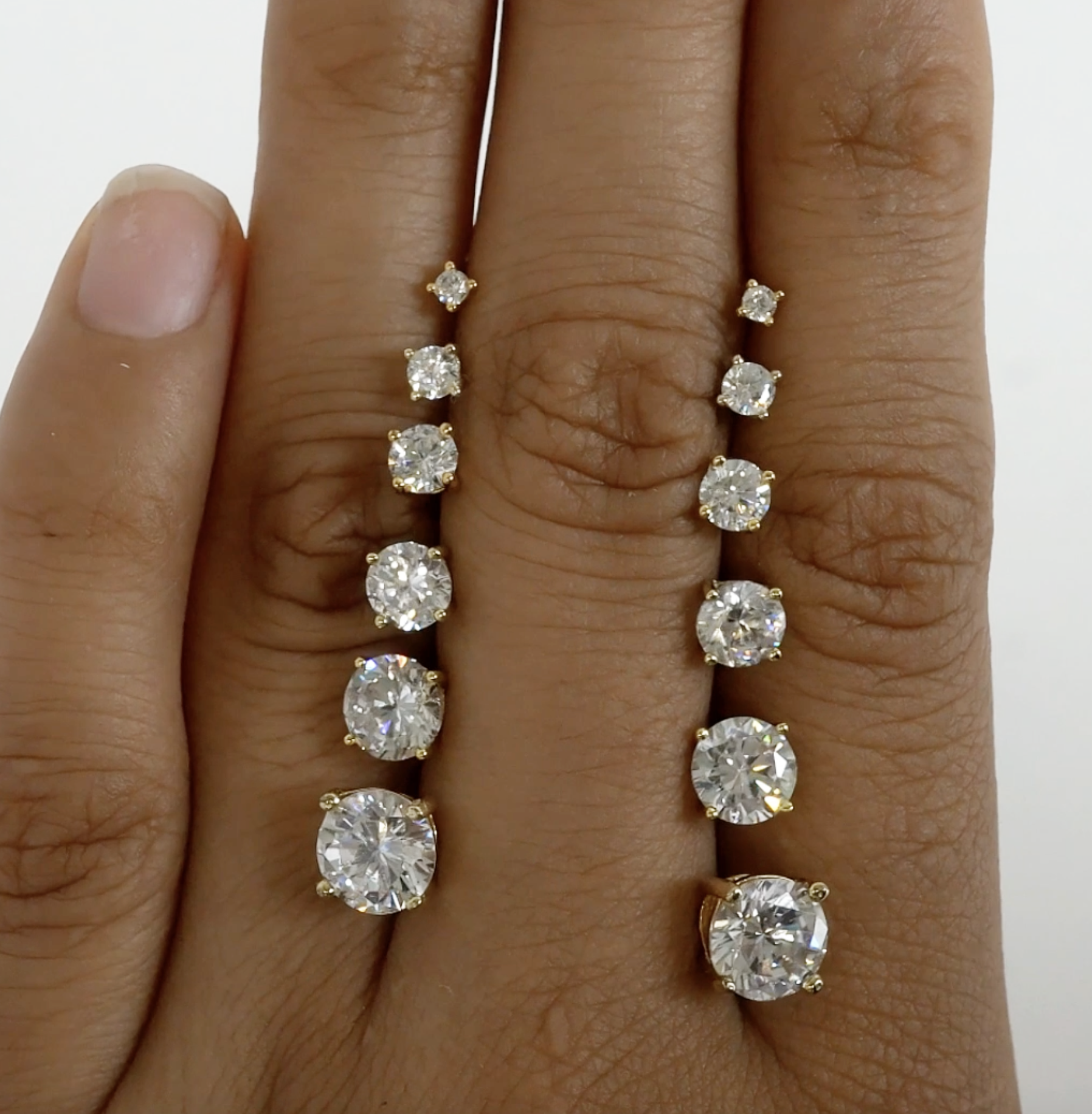 Close-up of hand displaying 14K Gold White Sapphire Studs