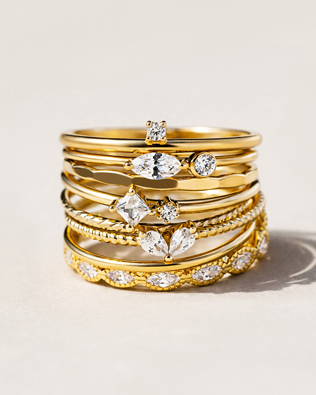 Shop AMYO gold stacking rings featuring dainty bands with sparkling cubic zirconia stones and textured gold details.