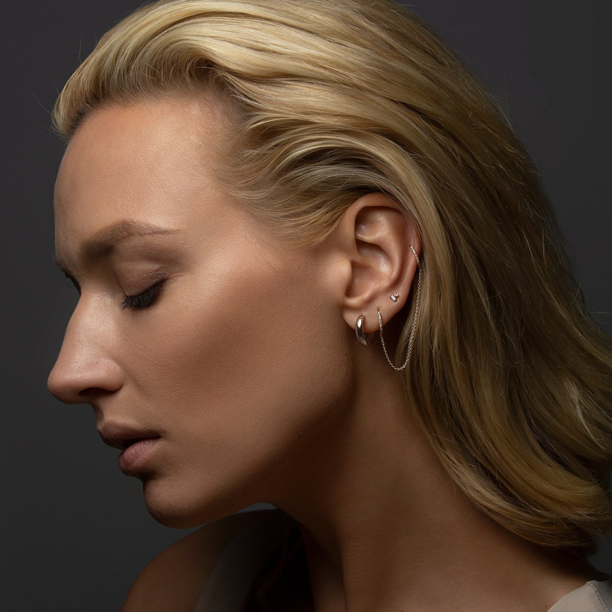 14K white gold baguette and round diamond duet studs shown on a model's upper lobe