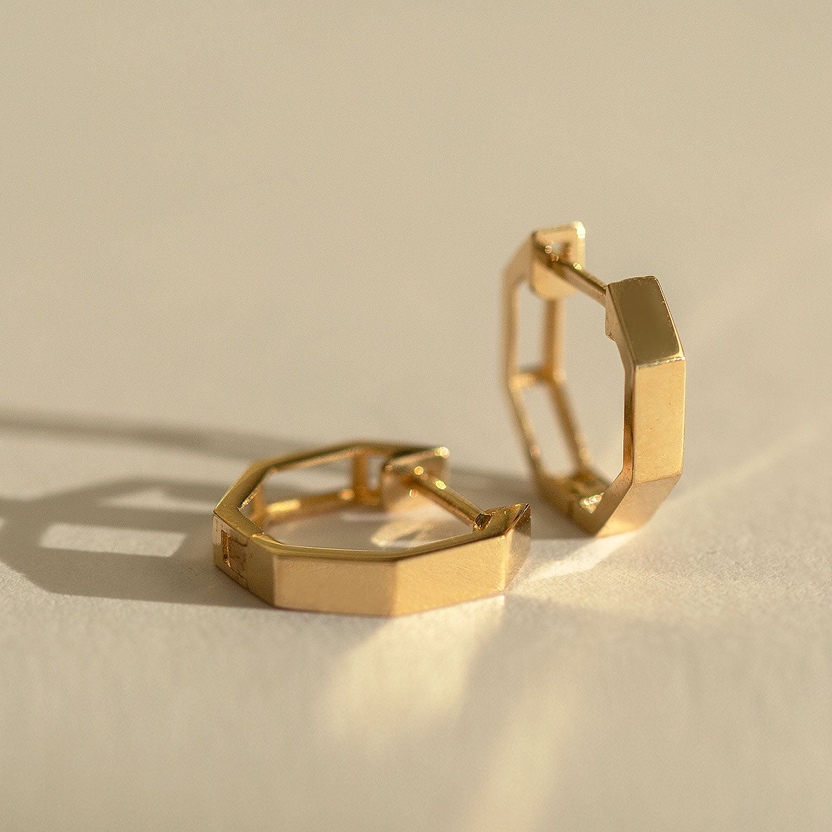 Close-up of earrings featuring 14K Solid Gold Octagon Huggie Earrings