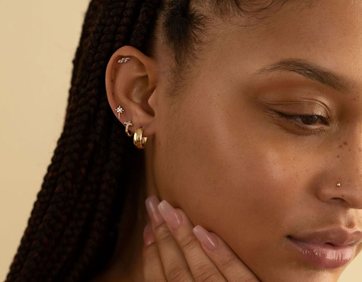 Close-up of a woman wearing gold vermeil and sterling silver earrings in her second and third piercings, styled in a minimalist ear stack.