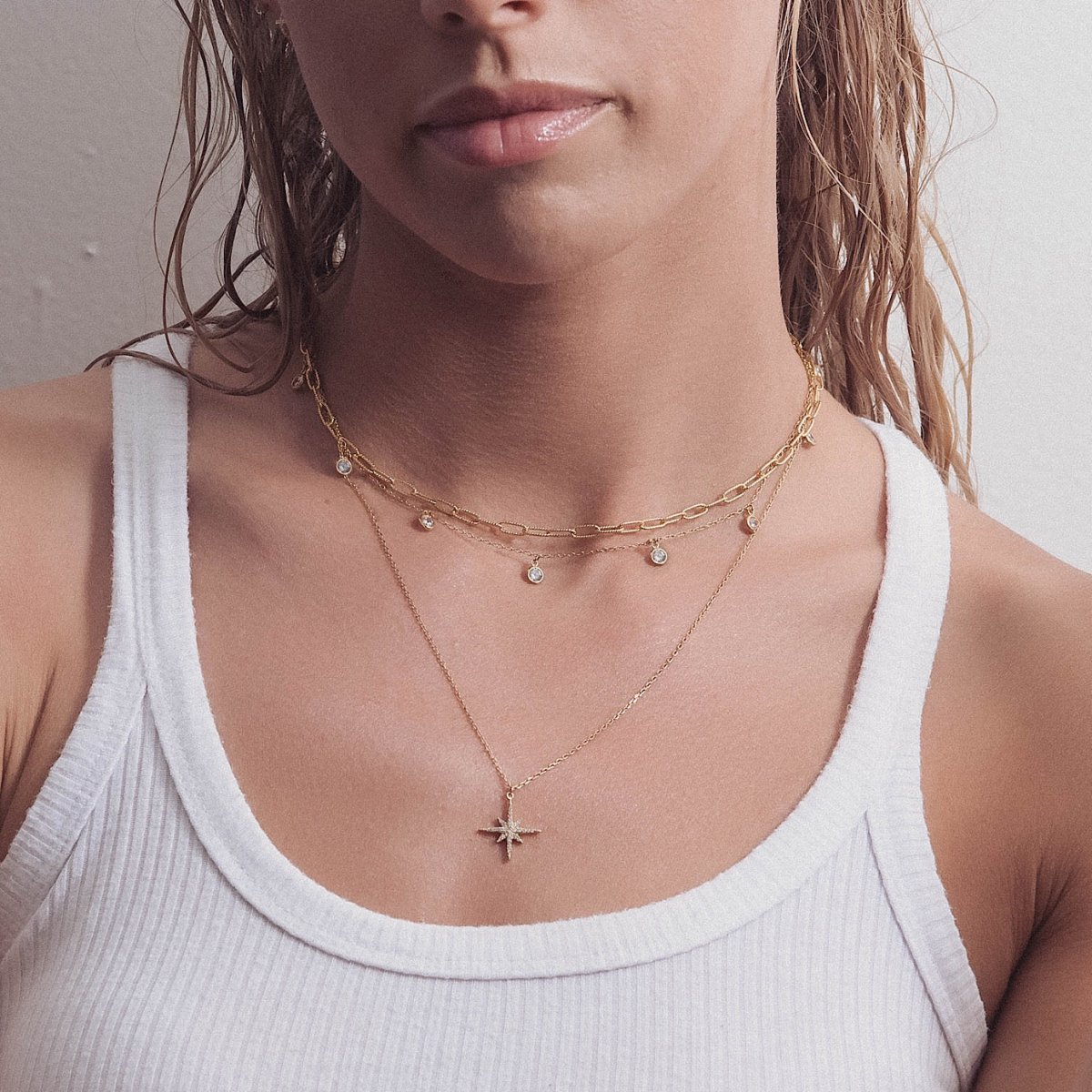 Gold vermeil starburst layered necklace trio with white zirconia, shown on a model's neckline