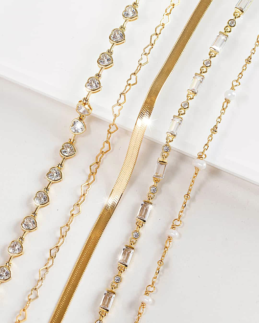 AMYO delicate gold bracelets with crystal bezels, pearls, and chain textures, designed for stacking, layering, and timeless minimalist everyday jewelry.
