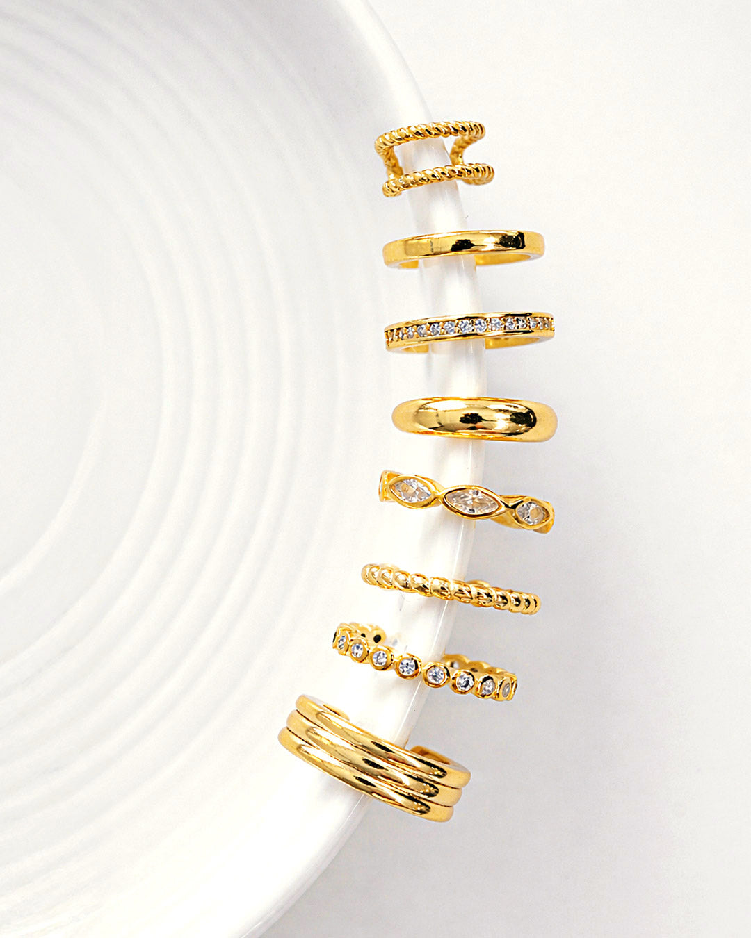 Gold vermeil Ear Cuffs from AMYO aligned on the side of a white dish.
