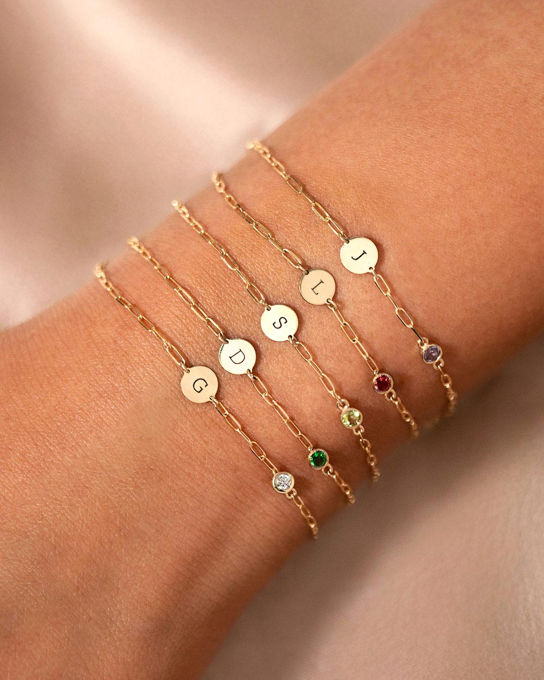 AMYO personalized gold bracelets featuring engraved initial charms and birthstone accents, perfect for meaningful jewelry gifting and everyday layering.
