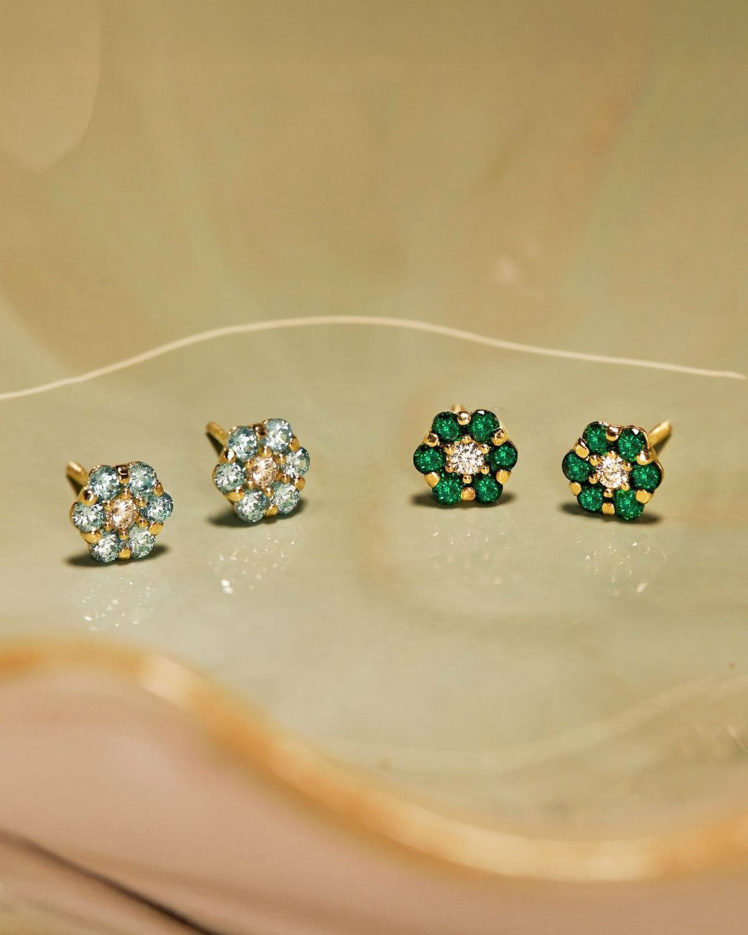 Delicate gold birthstone stud earrings with emerald green and aqua blue gemstones in floral designs from the AMYO birthstone jewelry collection.