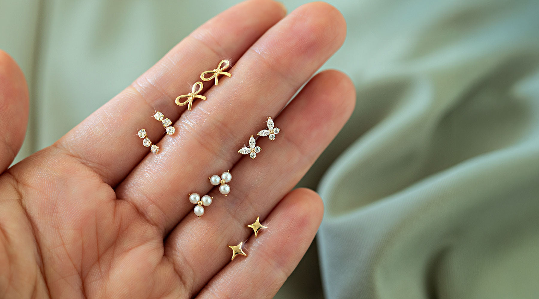 Shop AMYO 14k gold earrings featuring dainty studs in bow, pearl, star, and crystal designs, perfect for second holes, stacking, and everyday wear.