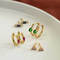 Close-up on earrings featuring Gold Vermeil Gemstone Baguette Huggie Earrings Ruby and other gemstone earrings. 