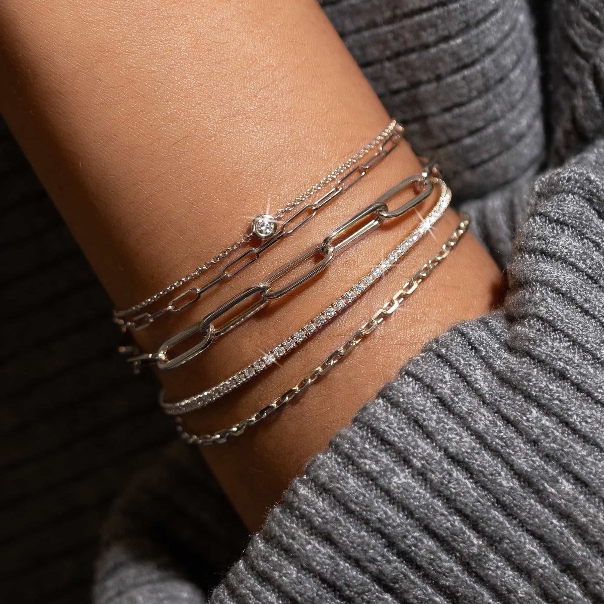 14K white gold bezel diamond chain bracelet stacked on a model's wrist