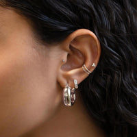 Close up of woman's ear featuring Pave Clover 14k white gold stud earrings and chunky silver hoop earring 