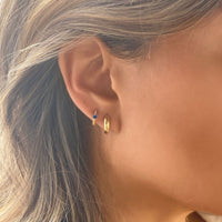 Close-up of woman's ear featuring Gold Vermeil Gemstone Bead Huggies Blue Sapphire CZ Crystal and Gold Chunky Hoop. 