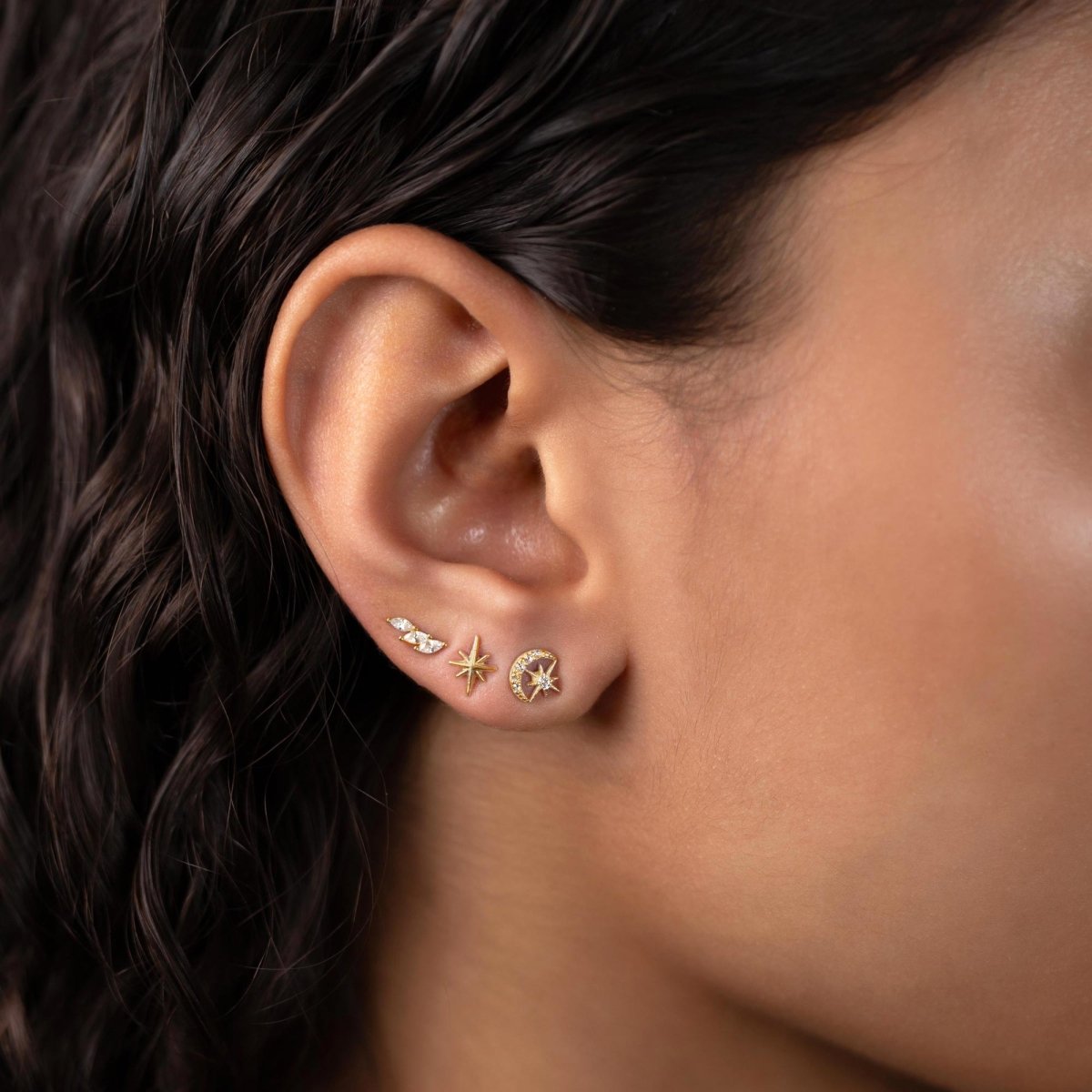 Gold vermeil moon and star studs with clear zirconia, styled in an ear stack on a model's lobe