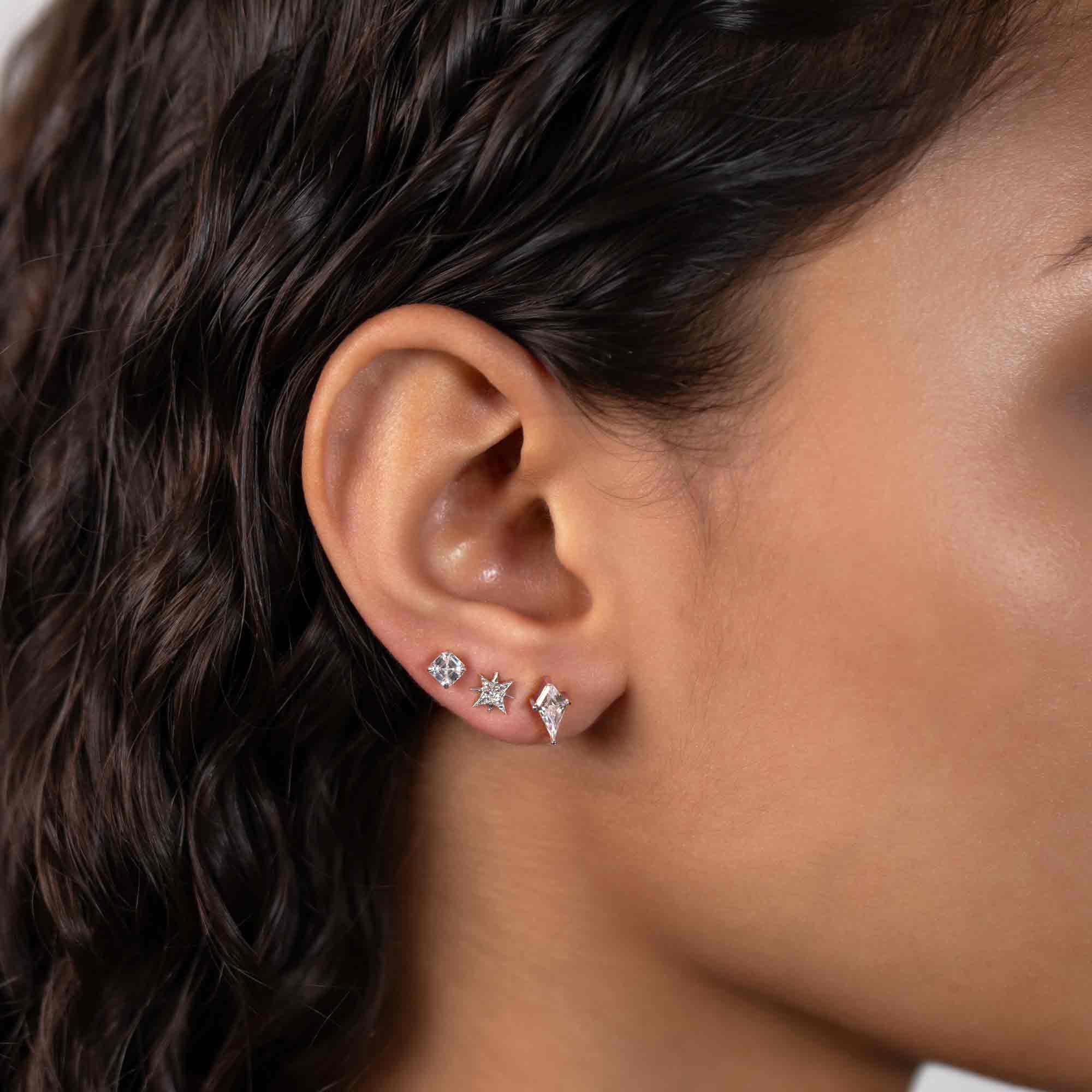 Sterling silver kite-shaped clear crystal stud shown on a model's lower lobe in an ear stack