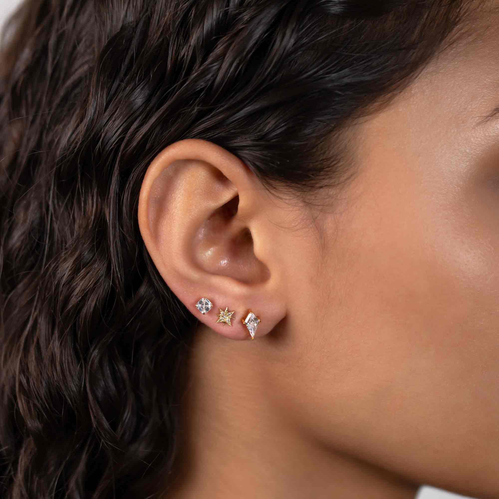 14K gold starburst pavé stud with white zirconia, shown on a model's lobe in an ear stack