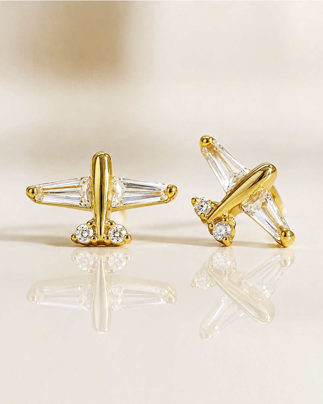 Detailed close-up of AMYO Airplane stud earrings in gold vermeil with white zirconia crystals.