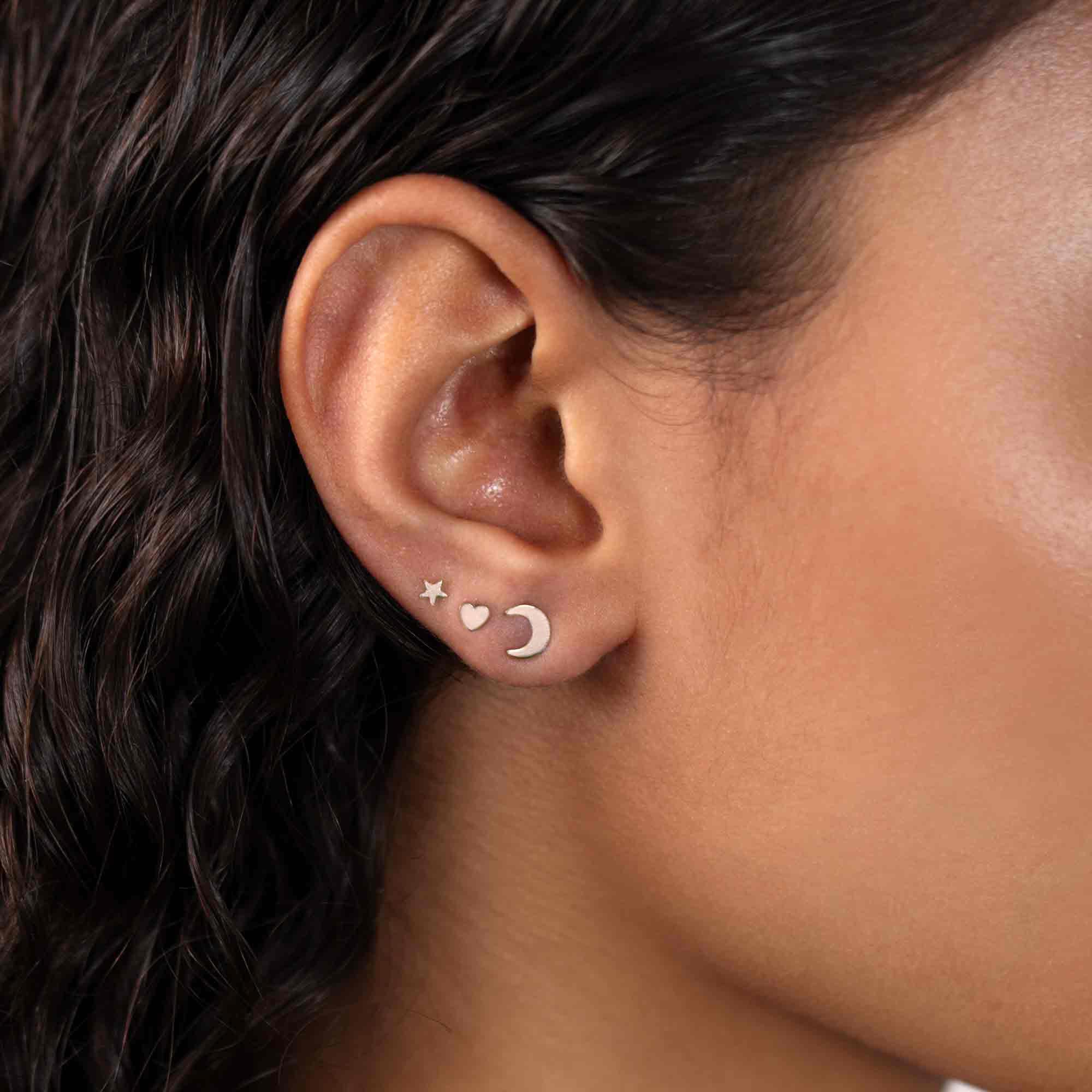 Sterling silver tiny star, heart and moon studs shown on a model's lobe