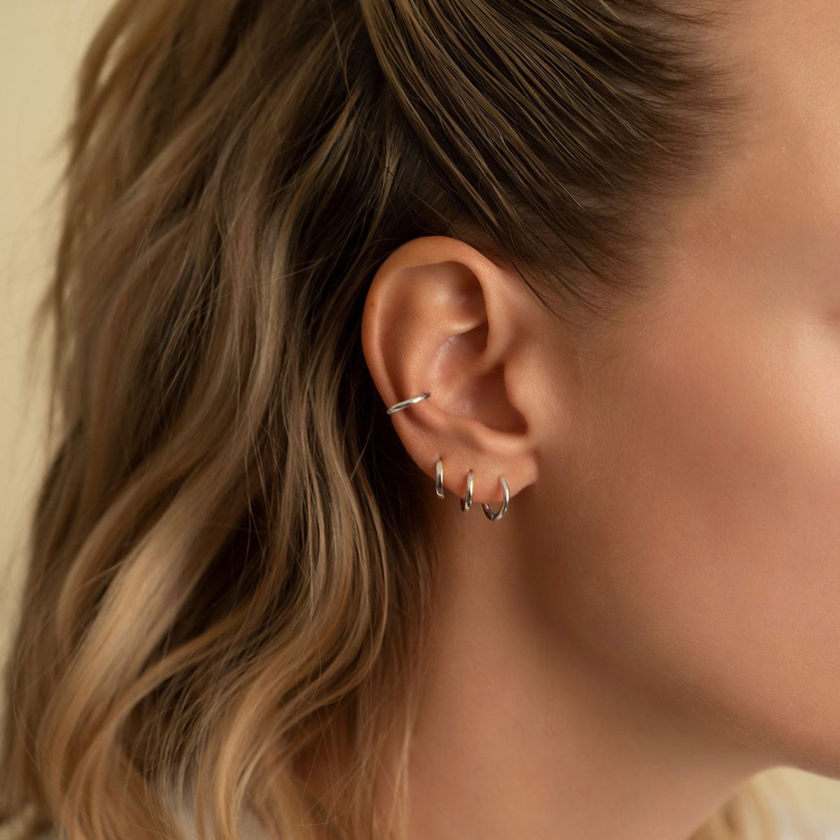 Close-up of sterling silver huggie earrings and conch. 