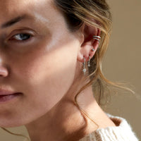 model wearing silver starburst huggie earrings, silver star flare huggie earrings, silver tiny starburst single stud, and silver eternity and pavé ear cuff set 