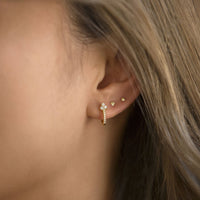 Close-up of woman's ear featuring Gold Vermeil Clover Pave Huggie Earrings and tiny gold studs. 