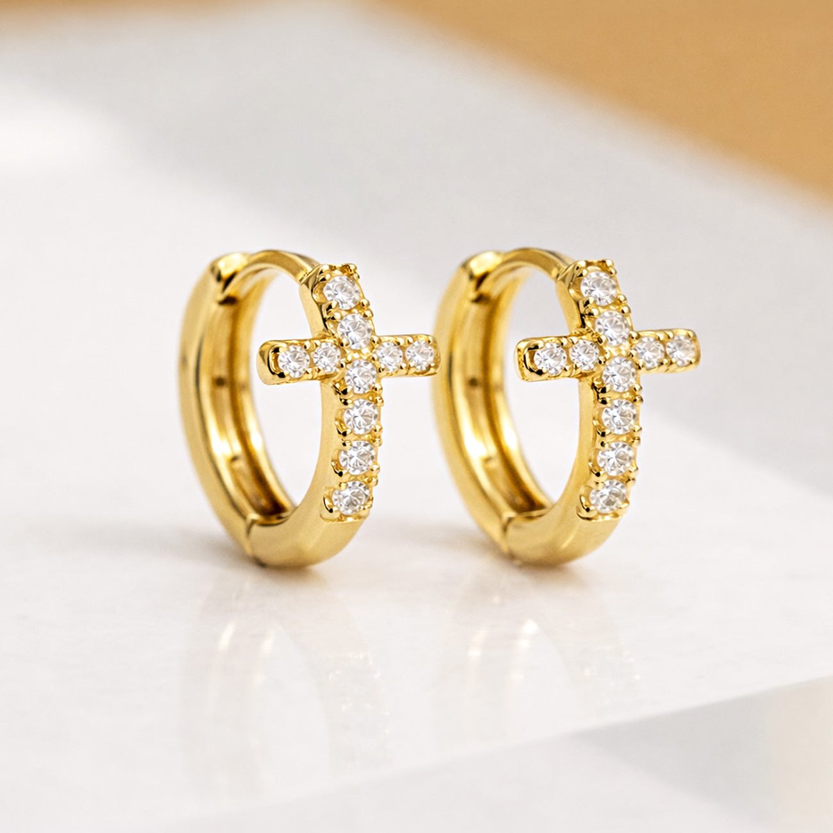AMYO's Cross Huggie earrings featuring Cubic Zirconia crystals crafted in Gold Vermeil.