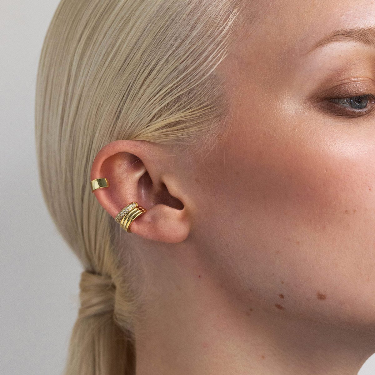 Close-up of a women's ear with gold vermeil ear cuffs for the helix and conch from AMYO