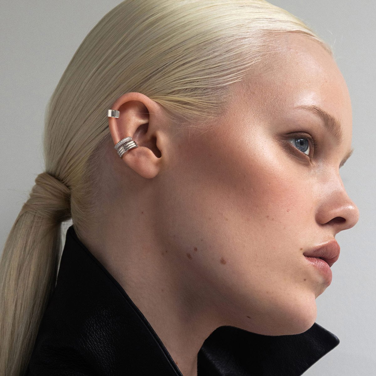 Close-up of a women wearing multiple sterling silver ear cuffs from AMYO on their ear
