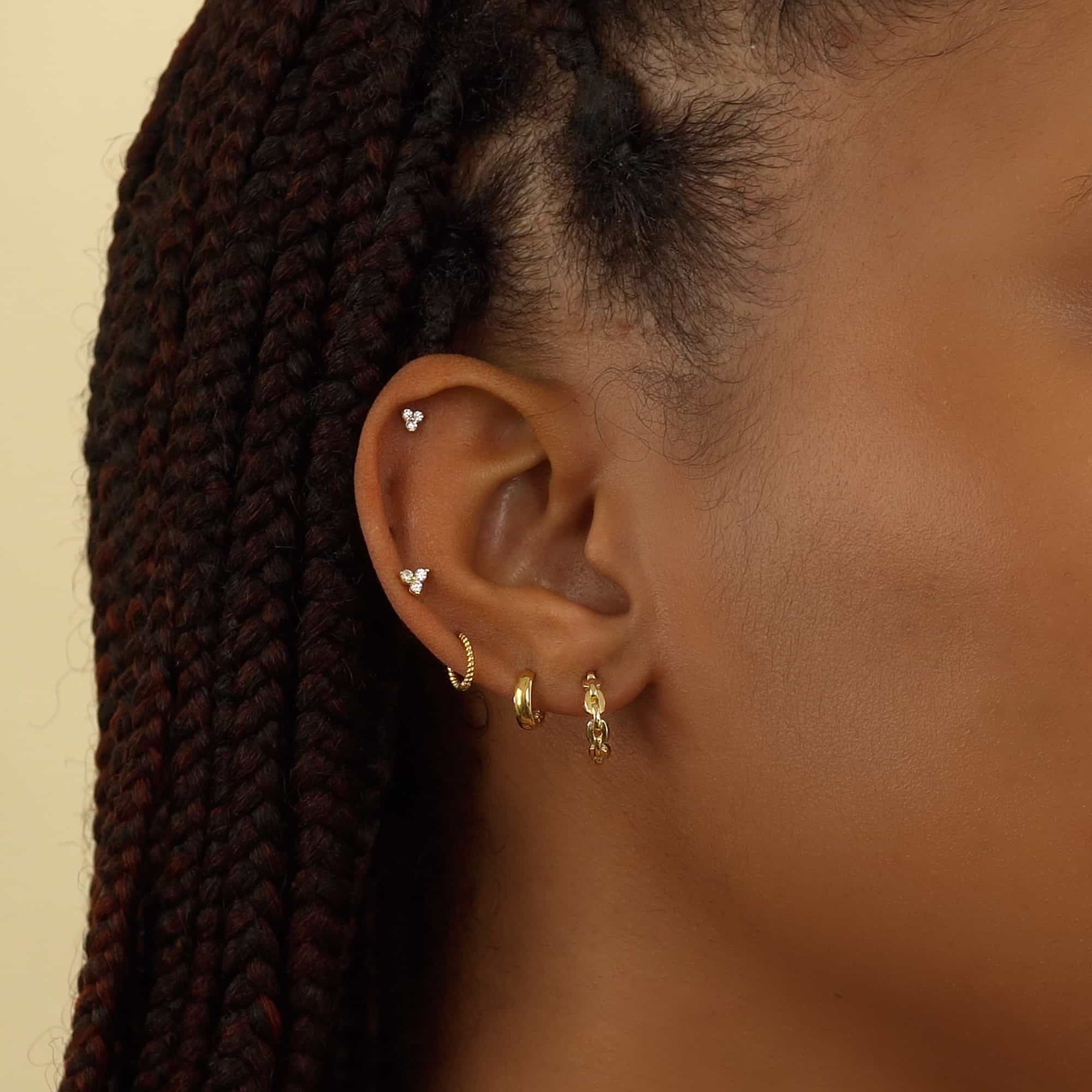 Close up of woman's ear featuring 14K Gold Tiny Clover Pave Stud and ear cuffs 