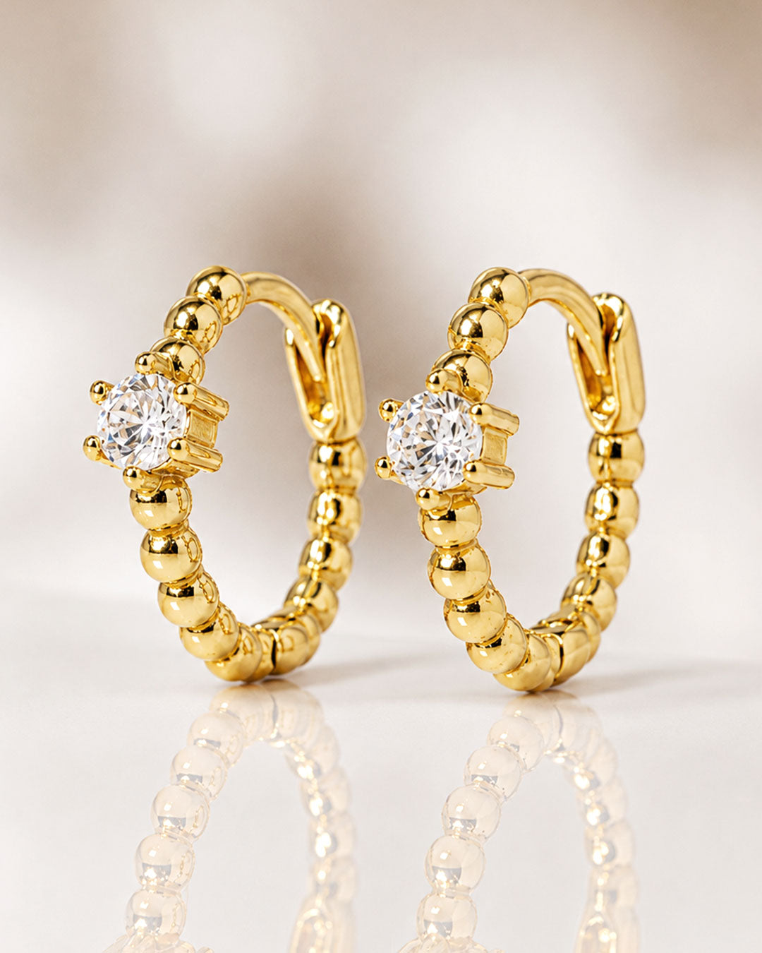 Close-up of pavé bead huggie earrings in gold vermeil from AMYO with white zirconia stones.