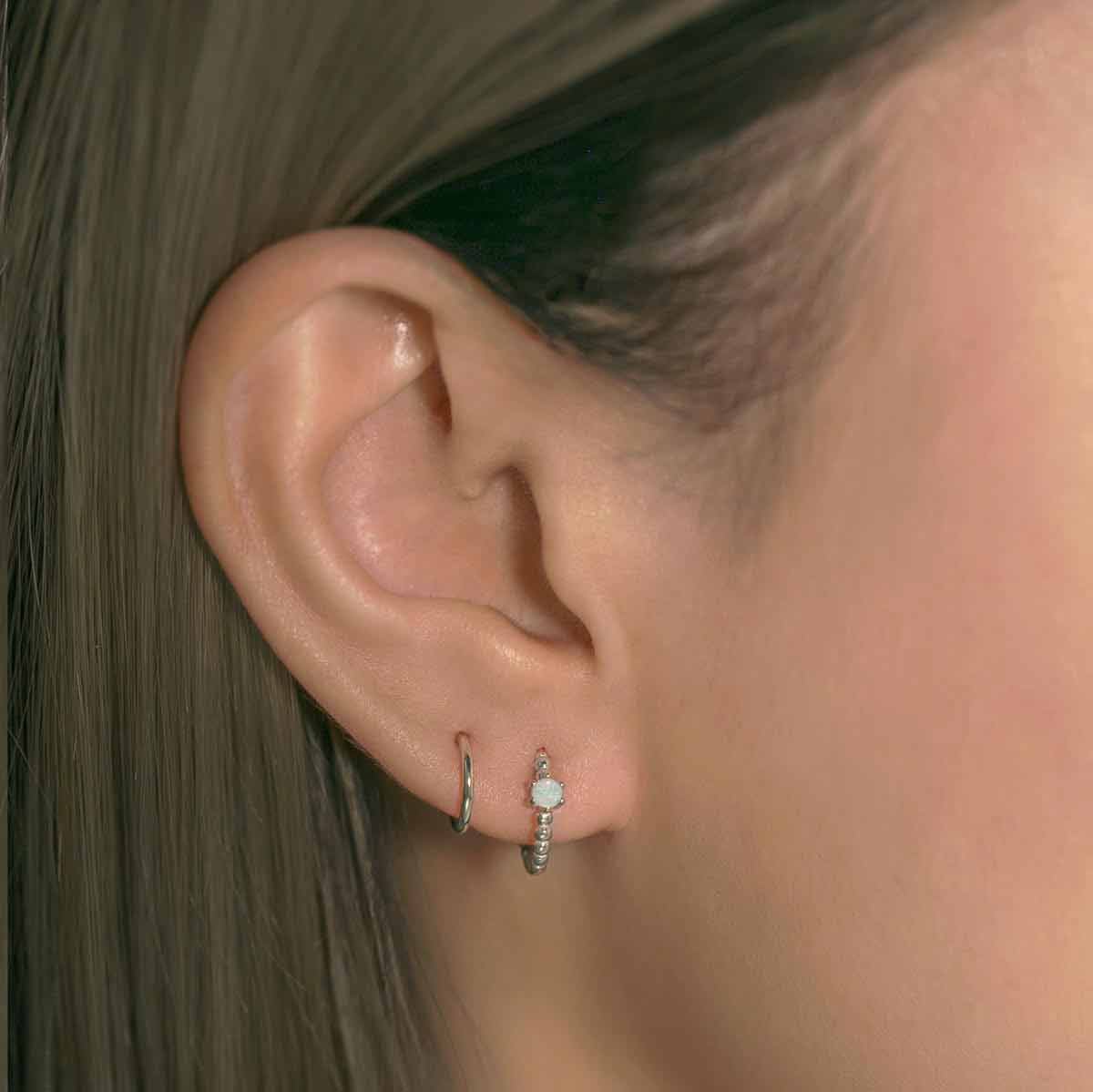 Close-up of woman's ear featuring Sterling Silver Gemstone Bead Huggies Opal and silver huggie. 